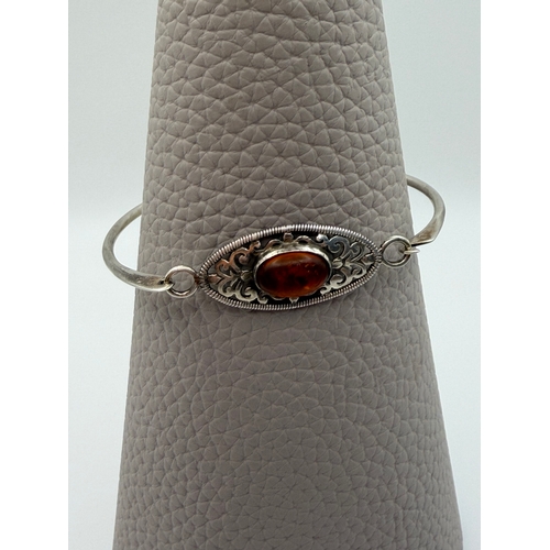 63 - A stamped 925 silver bangle with amber centre stone.
