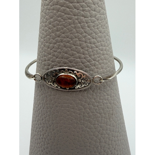 63 - A stamped 925 silver bangle with amber centre stone.