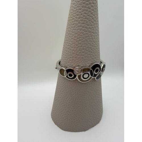 64 - A stamped 925 bangle featuring black and gold enamel circles design.