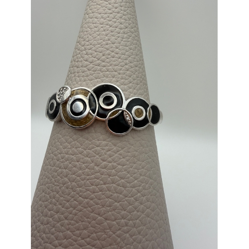 64 - A stamped 925 bangle featuring black and gold enamel circles design.