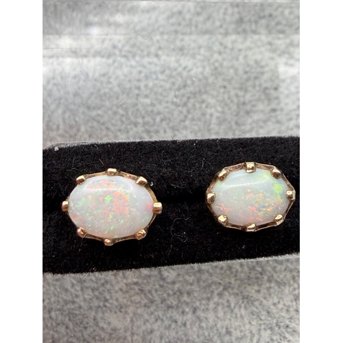 67 - A pair of hallmarked 375 9ct gold and opal studs with rare red colour.