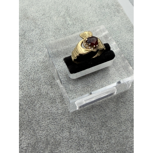72 - A hallmarked 375 9ct gold Claddagh ring with a garnet surrounded with diamonds. Size P.