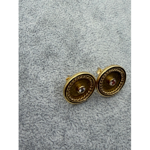 78 - A pair of tested 18ct gold earrings with central diamonds, est carat weight .2