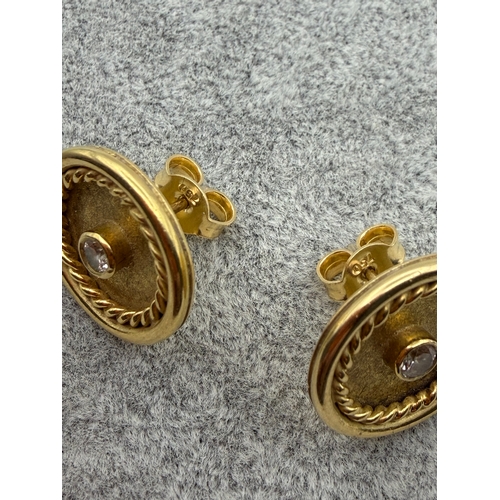 78 - A pair of tested 18ct gold earrings with central diamonds, est carat weight .2