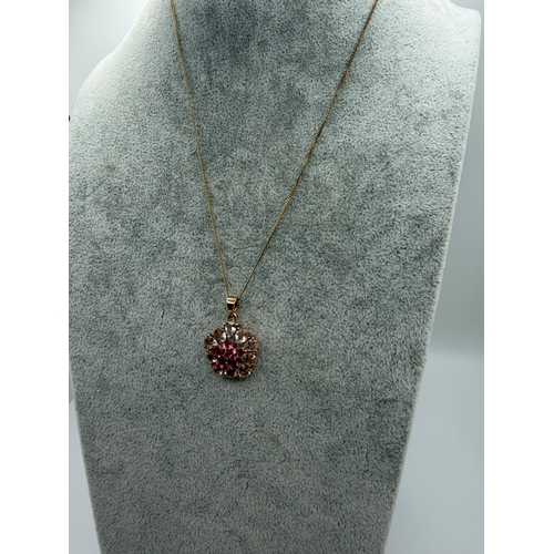 79 - A 9ct gold pendant with a floral design in light and dark pink stones on a silver necklace. Length 1... 
