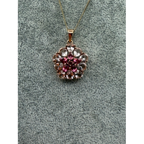 79 - A 9ct gold pendant with a floral design in light and dark pink stones on a silver necklace. Length 1... 