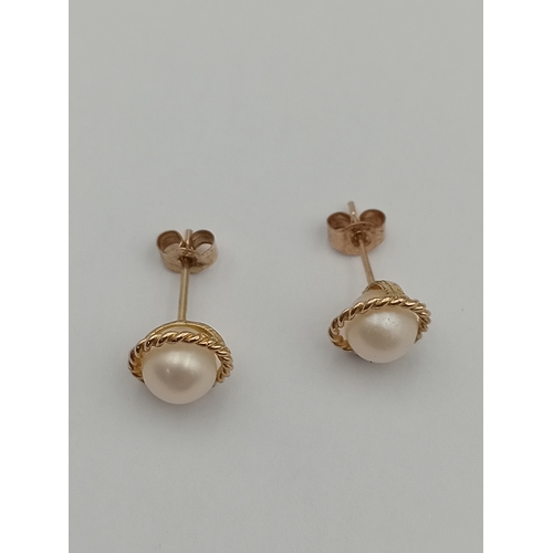 99 - A pair of tested gold earrings set with pearls.