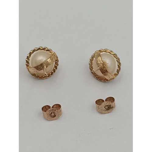 99 - A pair of tested gold earrings set with pearls.