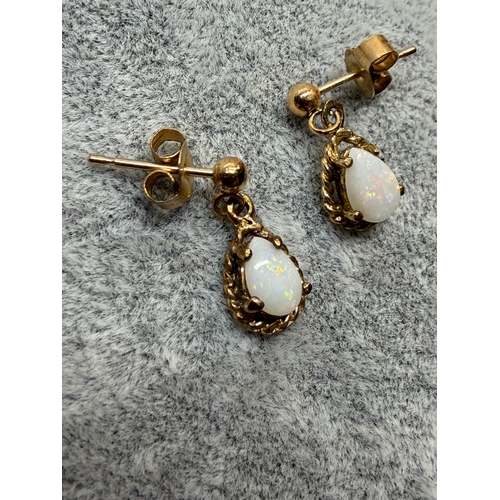 161 - A pair of tested 9ct gold earrings set with white Opal featuring red green and blue.