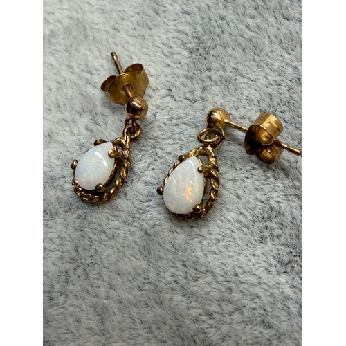 161 - A pair of tested 9ct gold earrings set with white Opal featuring red green and blue.