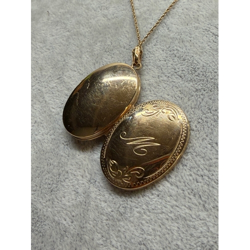 165 - A 9ct gold locket with a engraved floral pattern and an M monogram, fully hallmarked. Length 18 inch... 