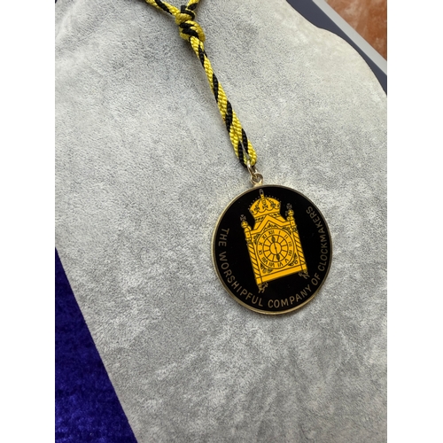 191 - A sterling silver medal featuring a black background with a gold enamel clock with words the worship... 