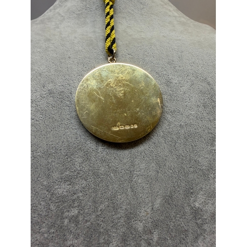 191 - A sterling silver medal featuring a black background with a gold enamel clock with words the worship... 