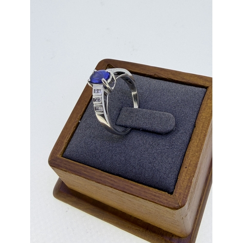 221 - A 18ct white gold ¾ carat oval tanzanite and cushion cut diamond dress ring. Size R 1/2. Weight 5.2g