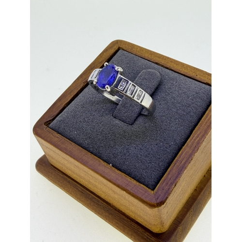 221 - A 18ct white gold ¾ carat oval tanzanite and cushion cut diamond dress ring. Size R 1/2. Weight 5.2g