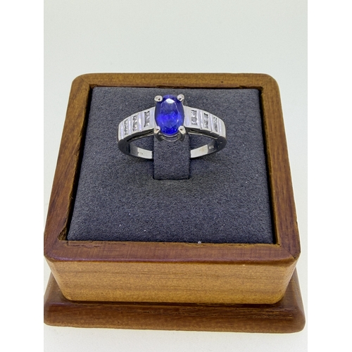 221 - A 18ct white gold ¾ carat oval tanzanite and cushion cut diamond dress ring. Size R 1/2. Weight 5.2g