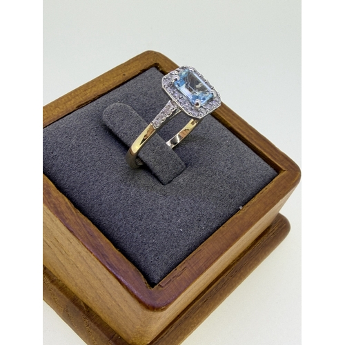 222 - A 9ct yellow gold ring with a cushion cut aquamarine surrounded by a halo of diamonds. Size Q and 1/... 