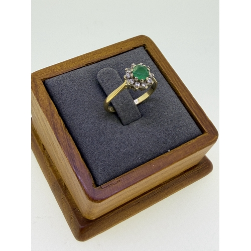 225 - A 18ct yellow gold and emerald ring with a halo of diamonds. Size M. Weight 3.2g