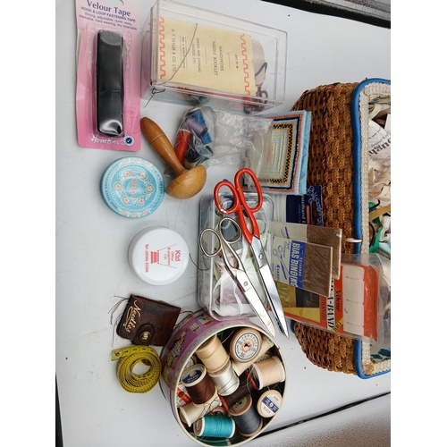 22 - A woven basket full of an assortment of sewing materials and accessories including scissors, needles... 