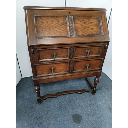 146 - An antique solid oak writing bureau, with fall front writing surface and 2 drawers. Height 40.5inche... 