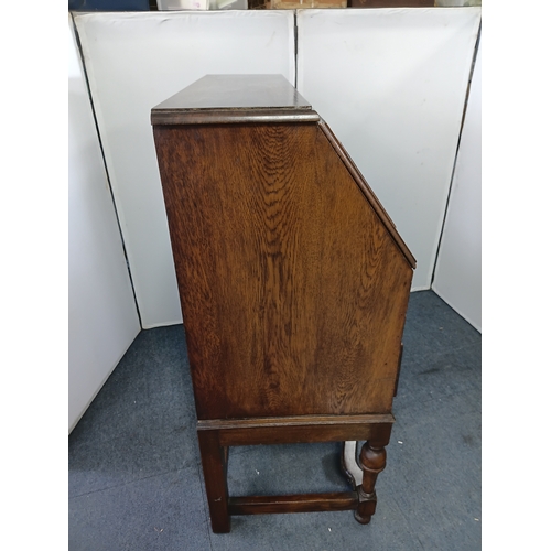 146 - An antique solid oak writing bureau, with fall front writing surface and 2 drawers. Height 40.5inche... 