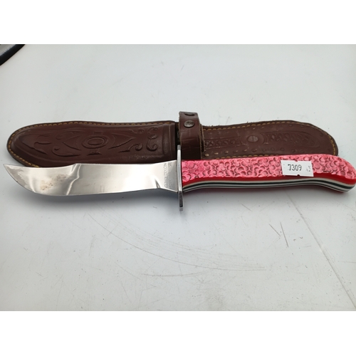 202 - A hunting knife with a 5inch stainless steel blade and a decorative pink handle with leather sheath.