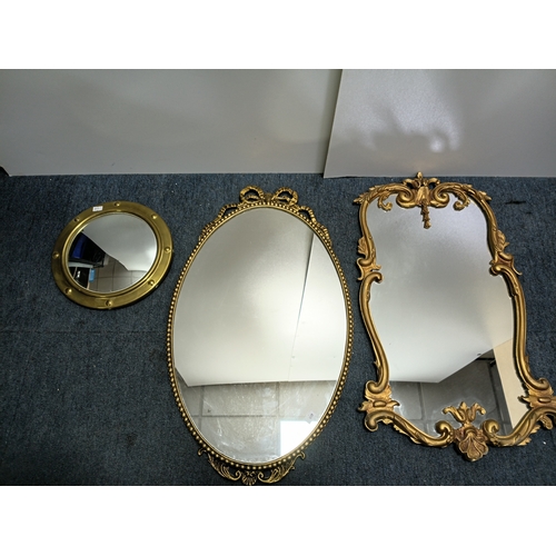 106 - A set of 3 gold gilt mirrors: a small brass port hole style mirror and 2 metal mirrors. The largest ... 