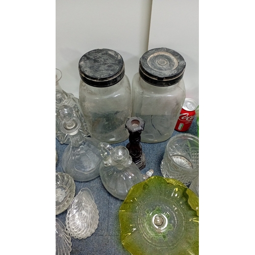 3 - A collection of decorative glass, including stoppered decanters and bottles, covered storage jars, a... 
