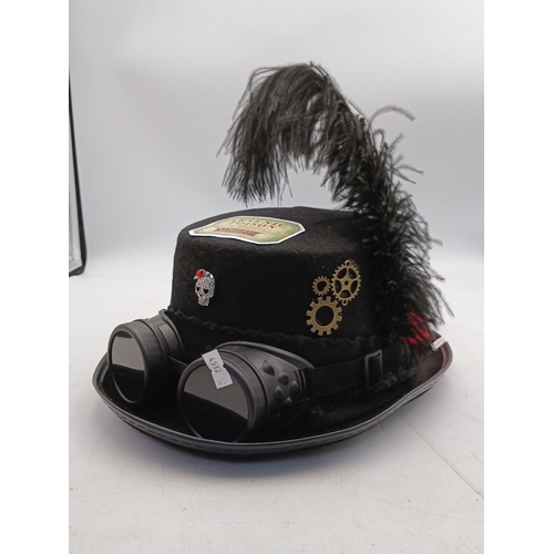 21 - Steampunk-inspired black felt top hat, embellished with feather plume, faux goggles, applied gear mo... 