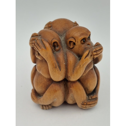 A hand carved wooden netsuke of three wise monkeys. Glass eyes. 1.5 inches tall.