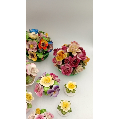 50 - A group of assorted porcelain floral encrusted ornaments and posy holders, including miniature vases... 