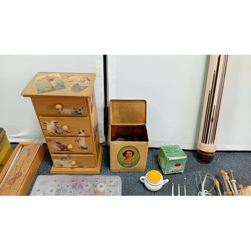 56 - A mixed group of sewing and knitting requisites, including a cat-decorated wooden drawer box, tins, ... 