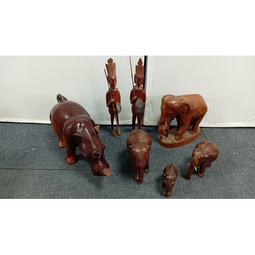 58 - A group of carved hardwood figures, including stylised elephants, a rhinoceros model, and a pair of ... 