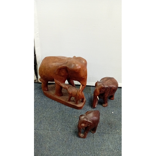 58 - A group of carved hardwood figures, including stylised elephants, a rhinoceros model, and a pair of ... 