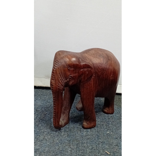 58 - A group of carved hardwood figures, including stylised elephants, a rhinoceros model, and a pair of ... 