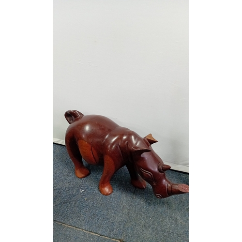 58 - A group of carved hardwood figures, including stylised elephants, a rhinoceros model, and a pair of ... 