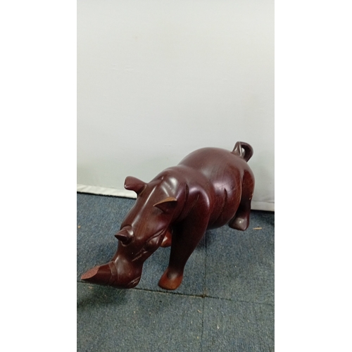 58 - A group of carved hardwood figures, including stylised elephants, a rhinoceros model, and a pair of ... 