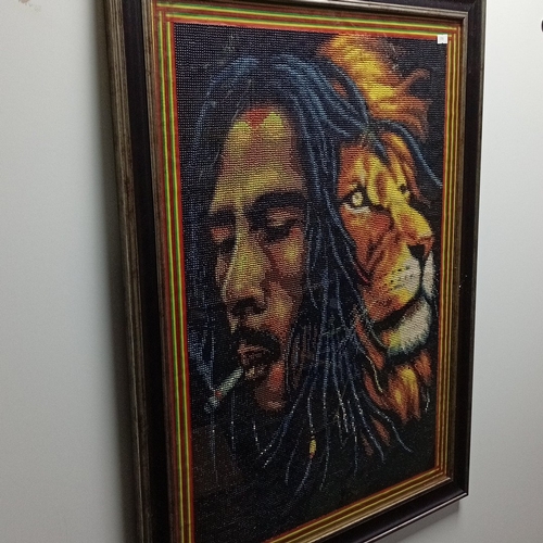 105 - Framed beadwork panel depicting a dreadlocked male head in profile with cigarette, paired with a lio... 