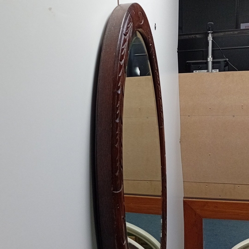 116 - Oval wall mirror in stained hardwood frame, the border carved with stylised foliate panels and oval ... 