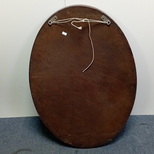 116 - Oval wall mirror in stained hardwood frame, the border carved with stylised foliate panels and oval ... 