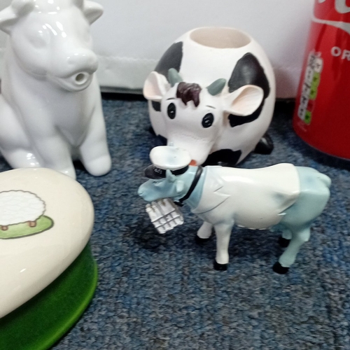 63 - A collection of novelty farm-animal ornaments in painted resin and ceramic, including cow and sheep ... 