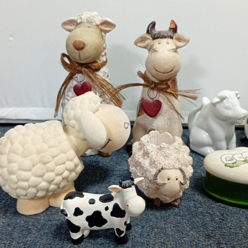 63 - A collection of novelty farm-animal ornaments in painted resin and ceramic, including cow and sheep ... 