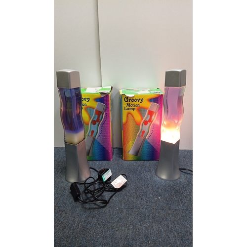 66 - A pair of “Groovy Motion Lamp” table lamps, each with a square-section base and cap framing a waiste... 