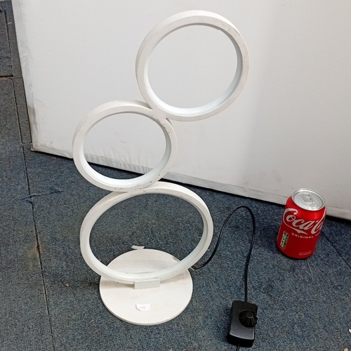 73 - Modern white metal table lamp with three circular LED light rings in graduated sizes, arranged asymm... 