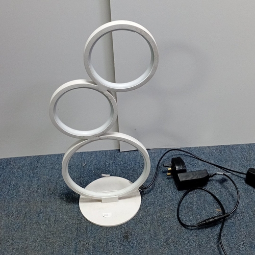 73 - Modern white metal table lamp with three circular LED light rings in graduated sizes, arranged asymm... 