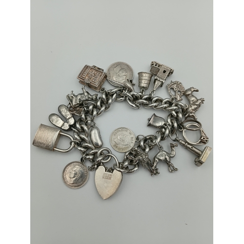 370 - A hallmarked silver curb link chain bracelet with a padlock clasp, including various silver charms f... 
