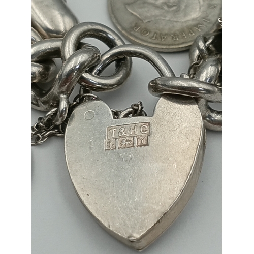 370 - A hallmarked silver curb link chain bracelet with a padlock clasp, including various silver charms f... 