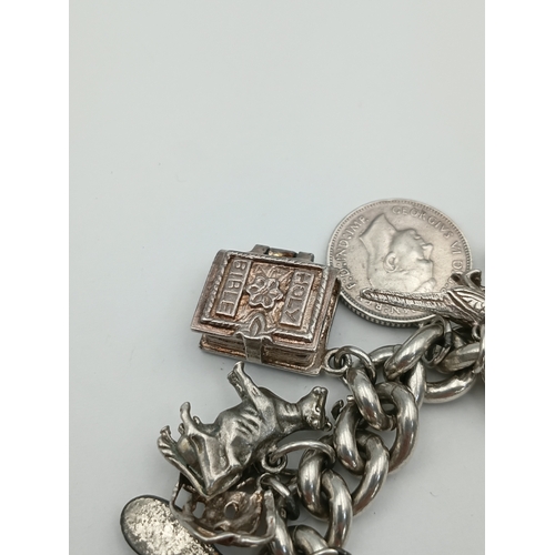 370 - A hallmarked silver curb link chain bracelet with a padlock clasp, including various silver charms f... 