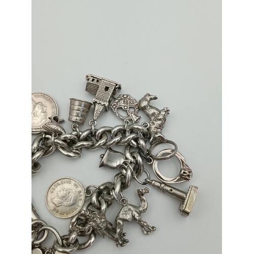 370 - A hallmarked silver curb link chain bracelet with a padlock clasp, including various silver charms f... 