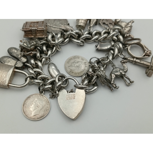 370 - A hallmarked silver curb link chain bracelet with a padlock clasp, including various silver charms f... 